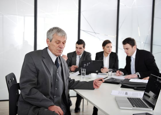 Senior businessman at a meeting. Group of colleagues in the background