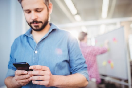 Young businessman texting on cellphone at creative office